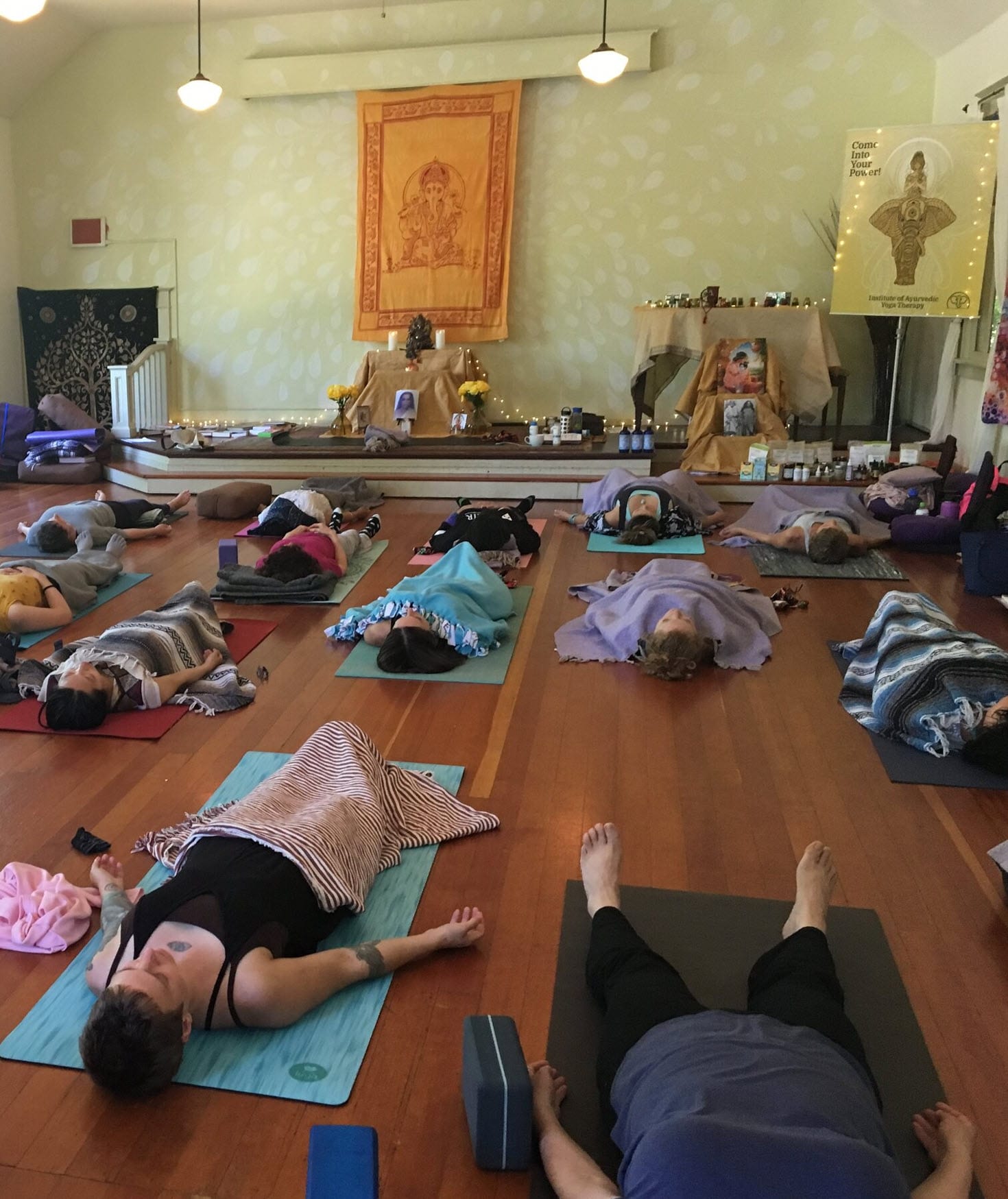 Sarasvati students in savasana on warm wood floors